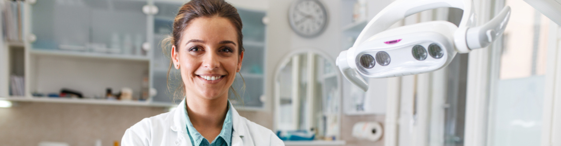A female dentist smiling with her arms crossed.